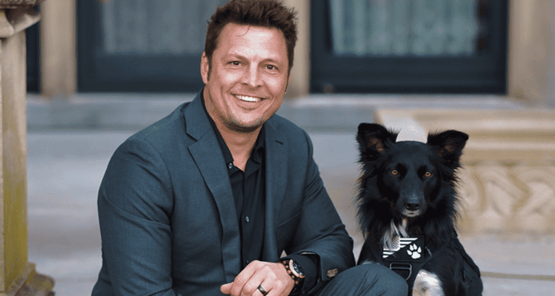 Photo of Zack Starr wearing a suit with his dog